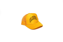 Load image into Gallery viewer, Gold Mesh trucker hat with Cloned embroidered in black collegiate letters in an Arc across the front panels, diagonalview.